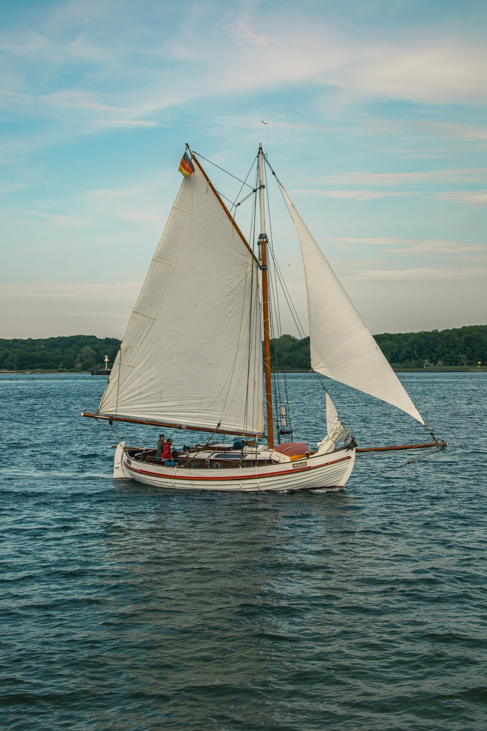 a sailboat in the open water near trees