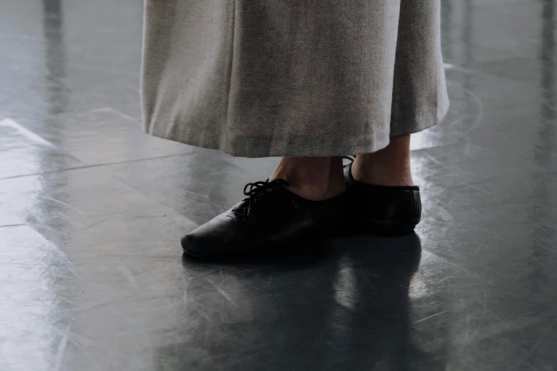 the feet of a person in black shoes and a coat