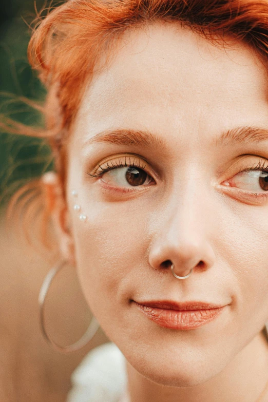 a beautiful red haired woman wearing big silver hoop earrings