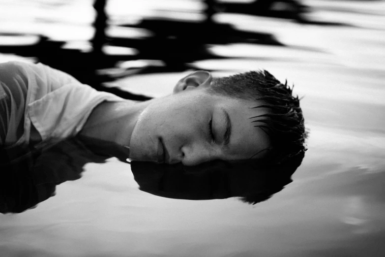 a person is laying in the water and has their eyes closed