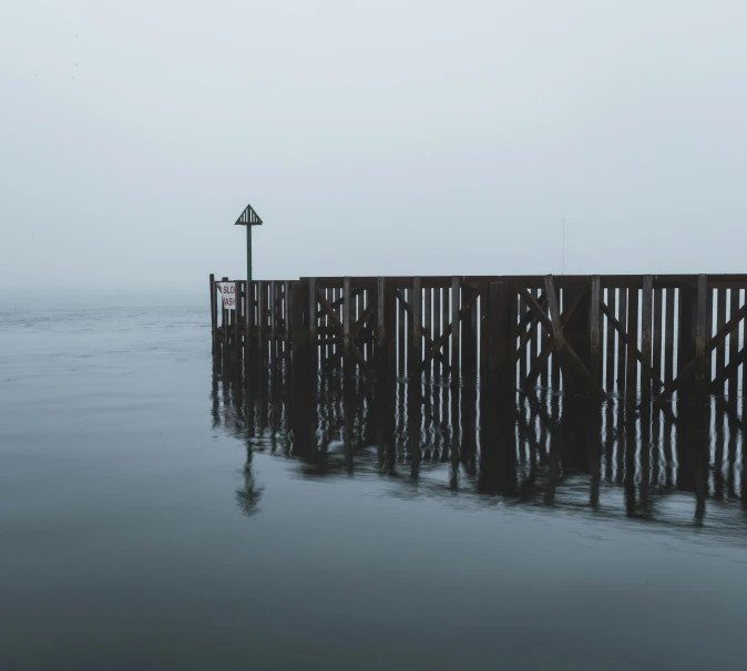 a long wooden dock stands in a misty sea