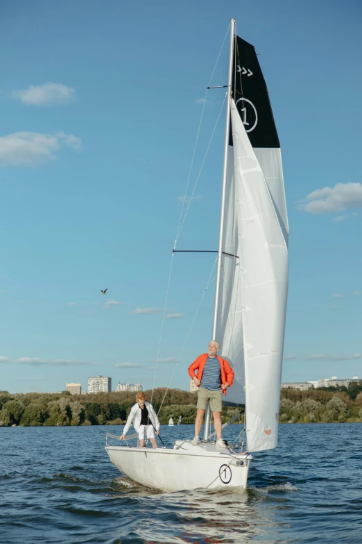 two men sailing a small sail boat on the water