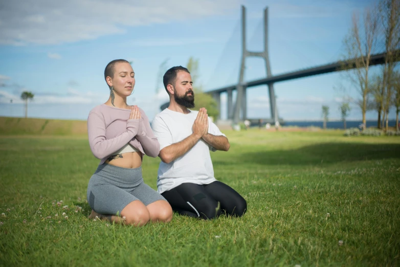 the two people are meditating in front of the bridge