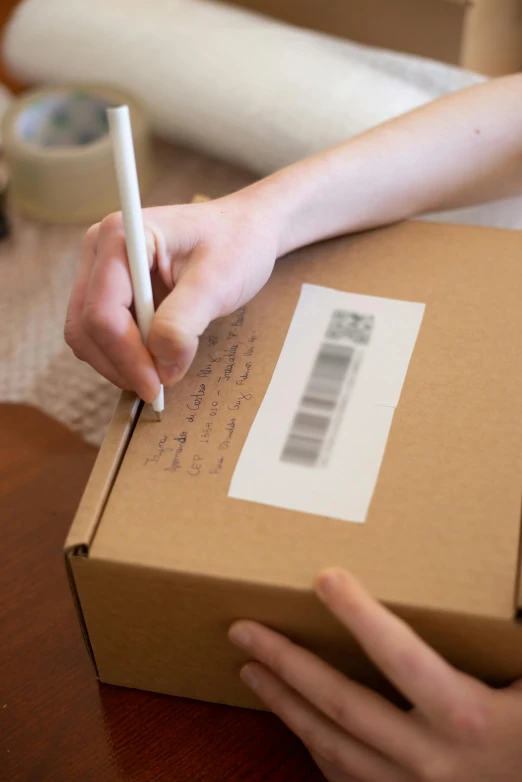 a person putting a pen in a cardboard box