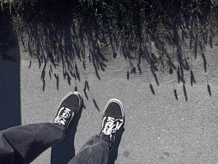 a person wearing sneakers and jeans walking in the sidewalk