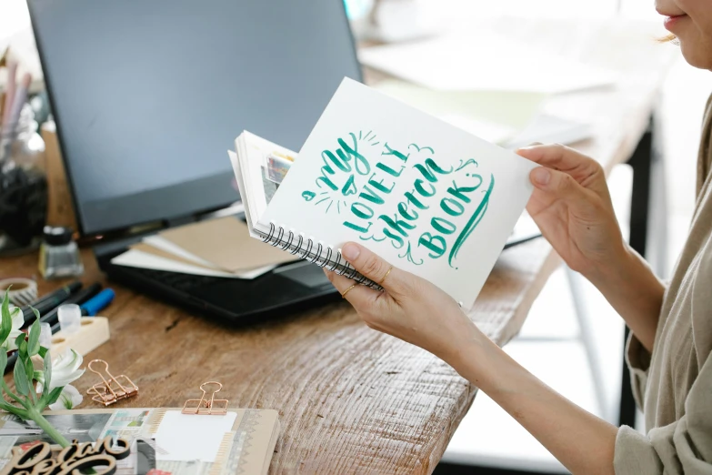 a woman holds a small card at her desk