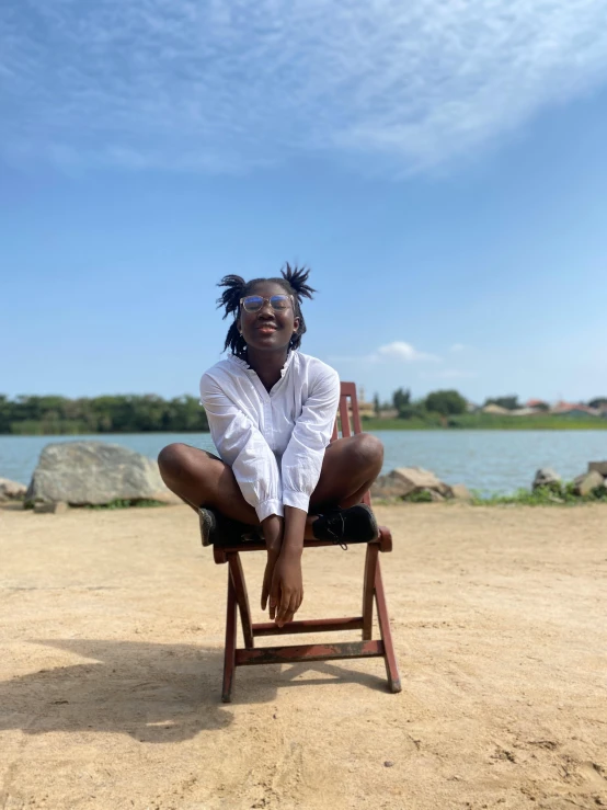 a girl poses on a chair on the beach