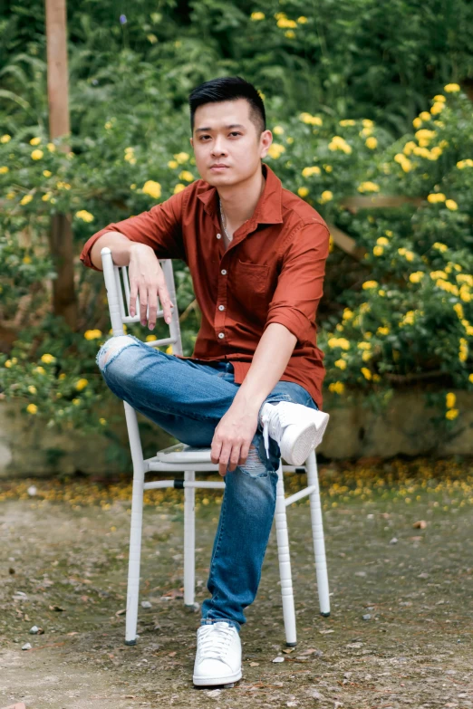 a man sitting on top of a chair next to flowers