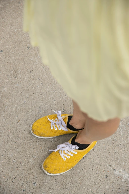 a person in yellow sneakers stands by the cement