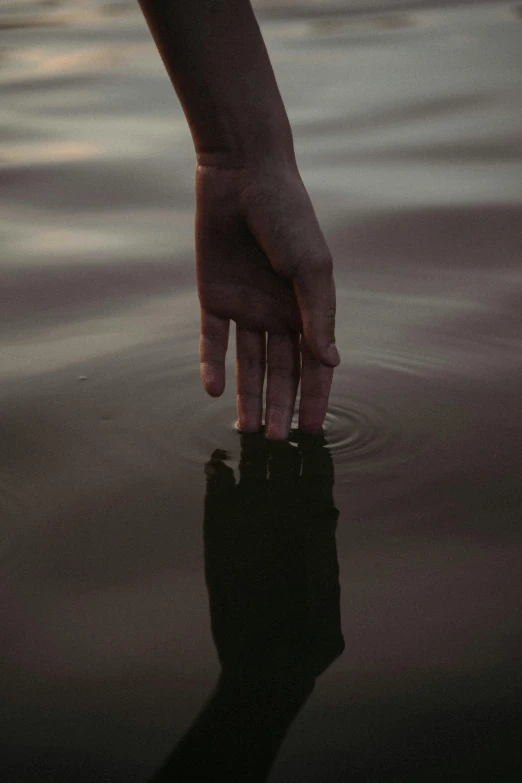 a person holding out their hand and reaching for the water