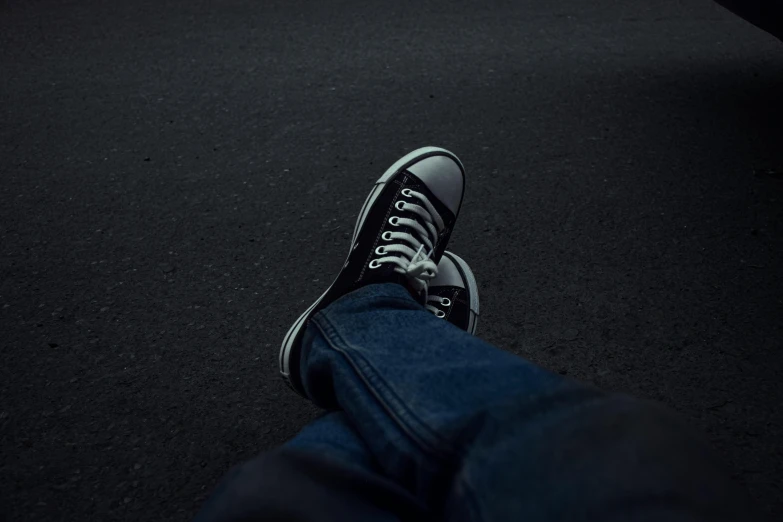 a pair of jeans, shoe and black sneakers laying down