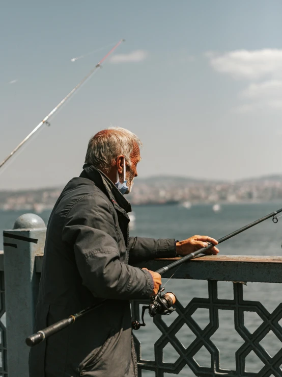 an elderly man fishing from a pier with his pole