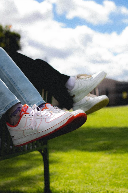 the legs and shoes of someone sitting on a park bench