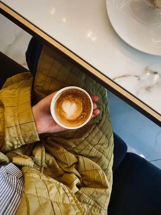 someone holds up their mug with the shape of a heart