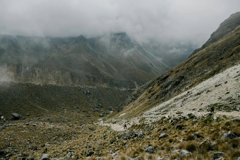 a rocky cliff side with some hills in the background