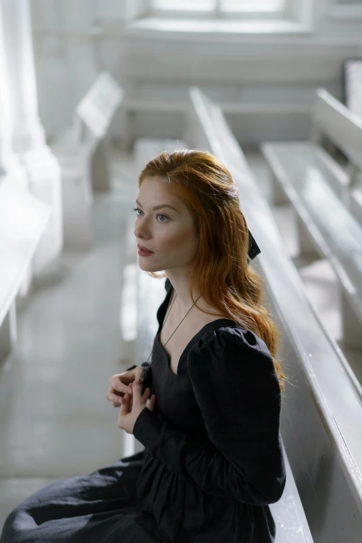 a girl in a black dress sitting on a bench