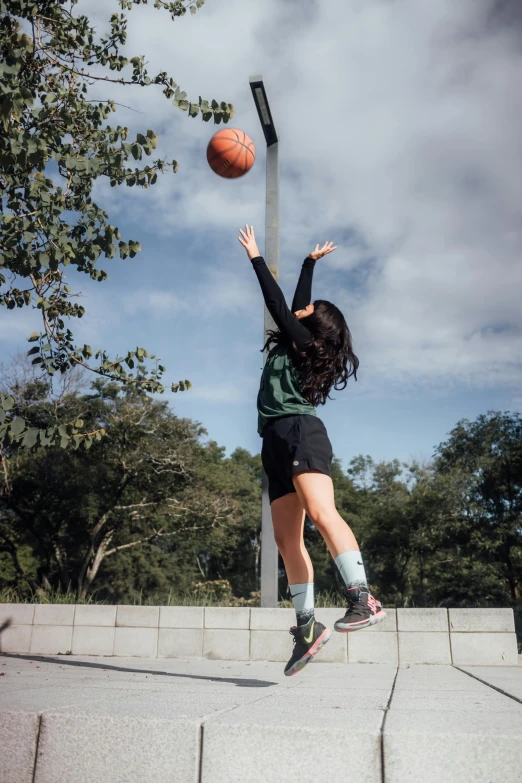 a woman jumping up into the air to grab a basketball