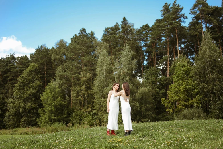 two women hugging each other outside with trees in the background