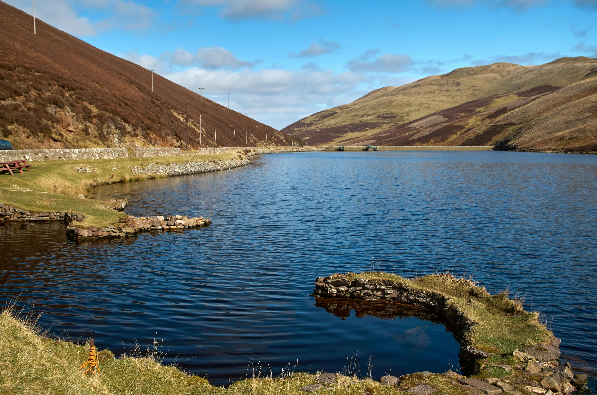 a lake is surrounded by mountains and a few houses