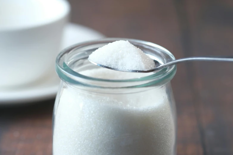 a small glass jar with sugar inside sits on a table