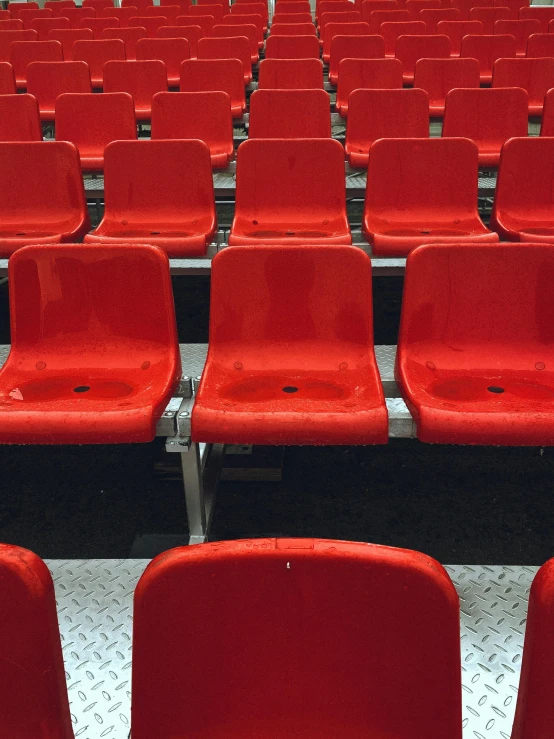 several rows of red stadium seats in a large room