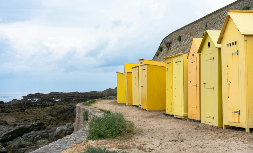 the yellow and green sheds are beside the rock shore