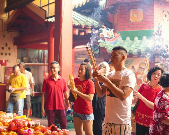 several people standing around a market in front of a large red building