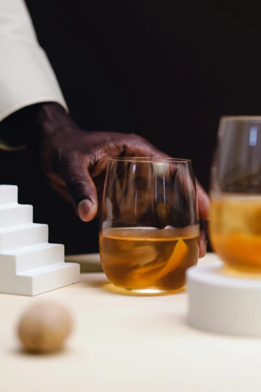 a hand holding a glass of wine while sitting on a table