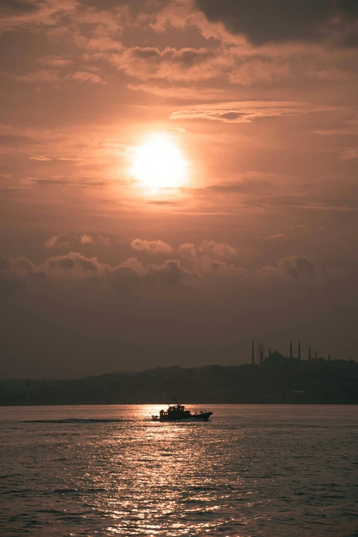 a boat travels along the ocean as the sun rises over some distant buildings