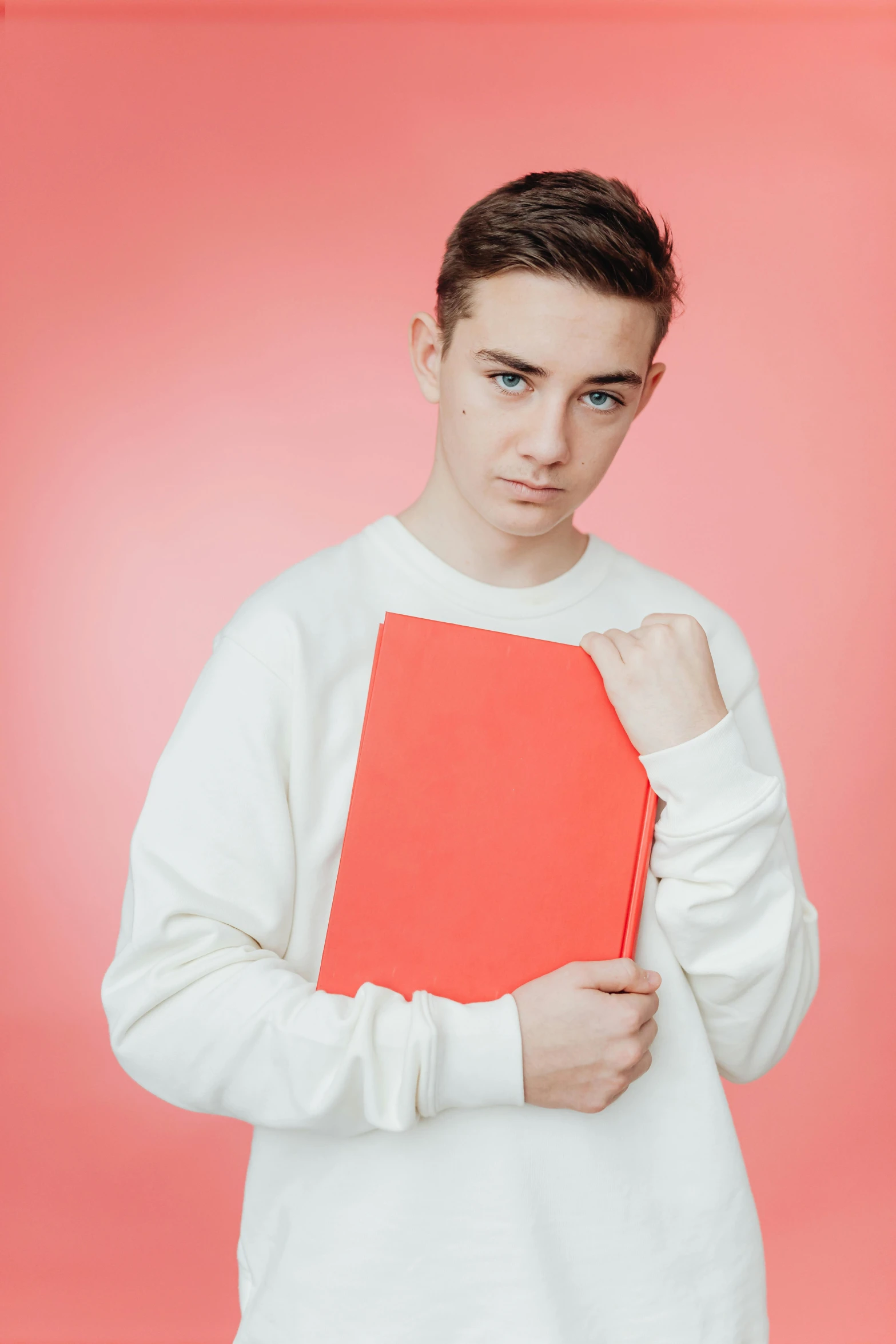 a boy with a red folder in front of a pink background