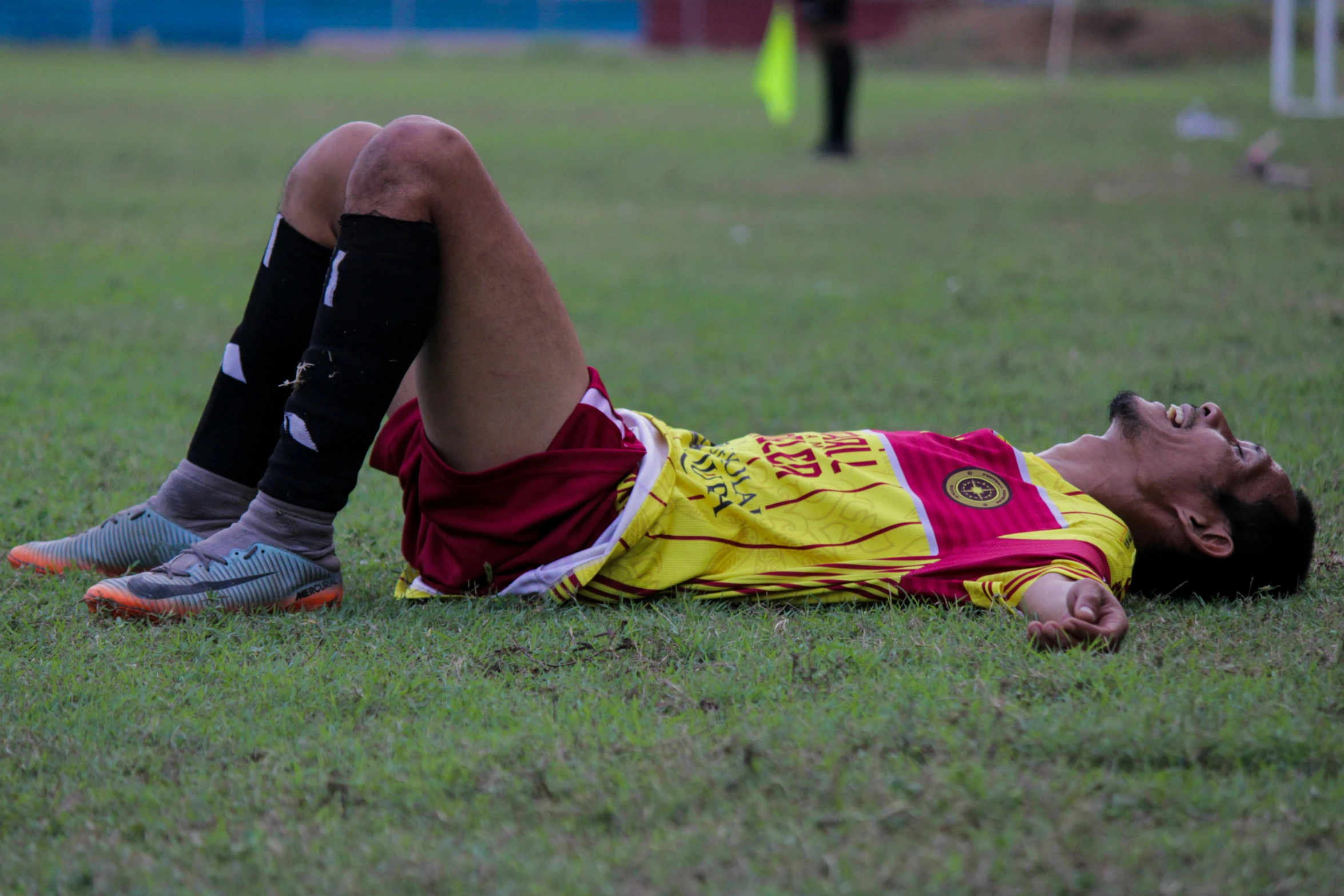 a man laying on top of grass wearing soccer uniforms