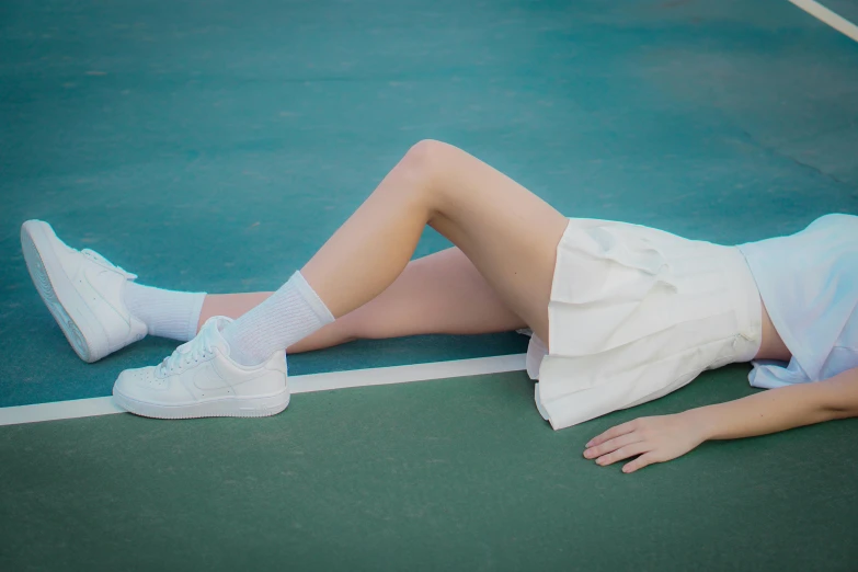 a  is laying on the tennis court wearing her tennis shoes