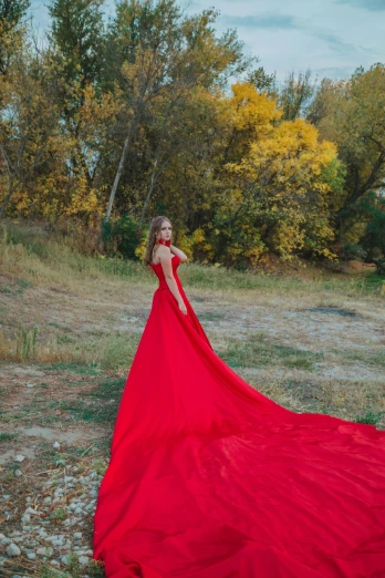 a woman in a red dress standing near a river