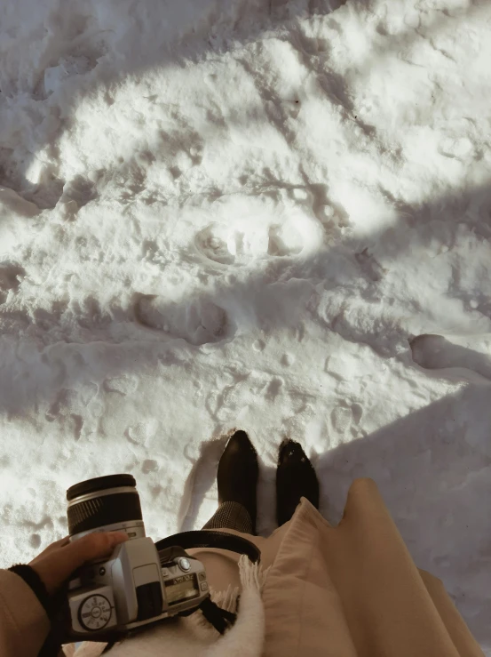 a person holding a camera while laying in the snow