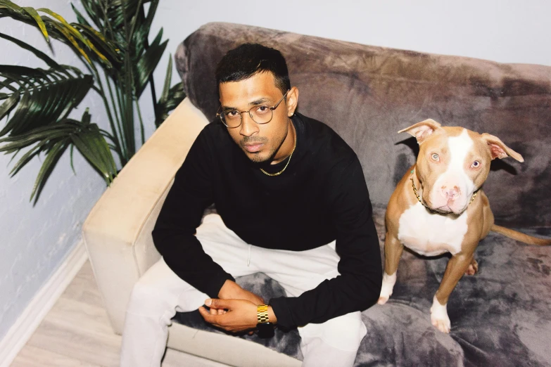 a man sitting on a couch with a brown and white dog