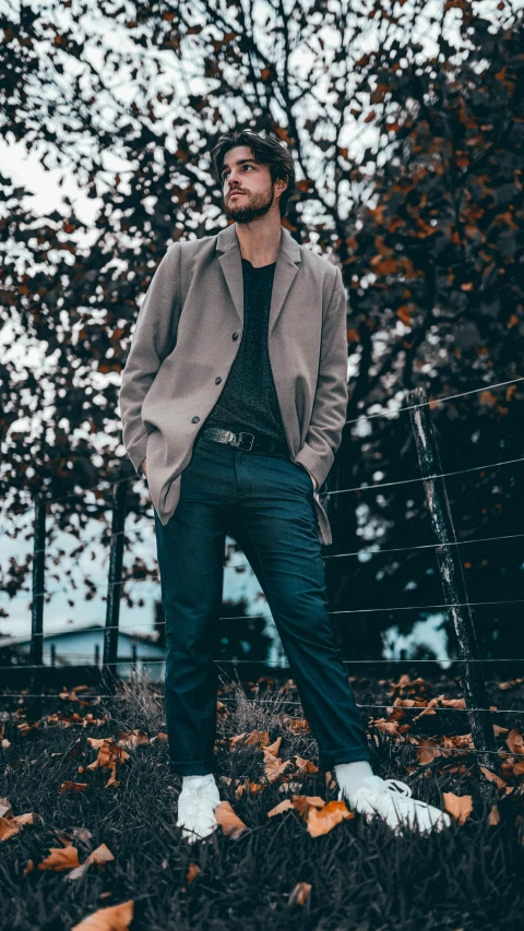 a man in sweater and shoes poses on a hill