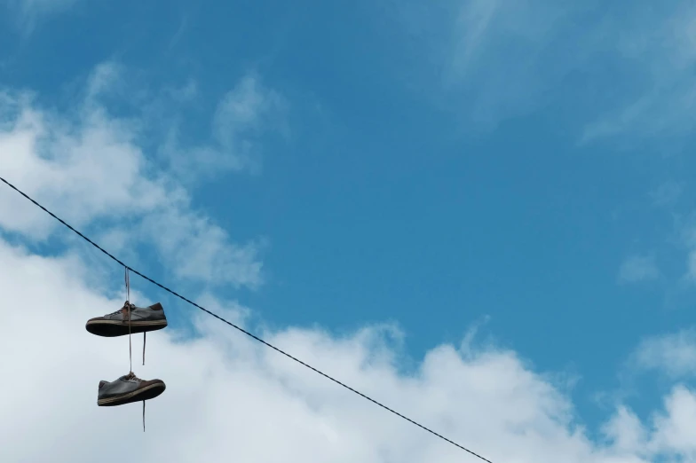 two old worn brown shoes hang in the air