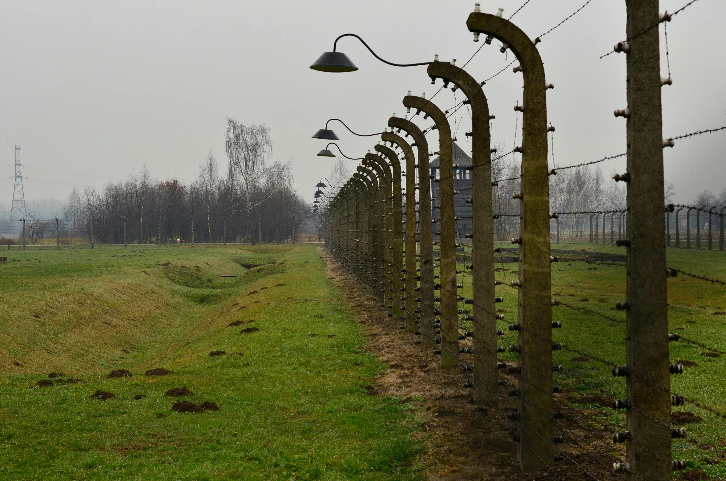 a line of lights along the fence of a green grassy field