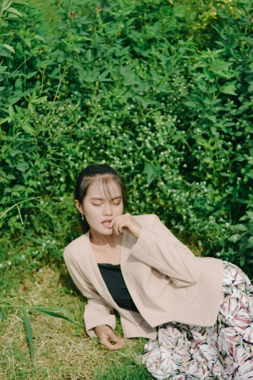 a woman sitting on the ground outside wearing a long, floral skirt