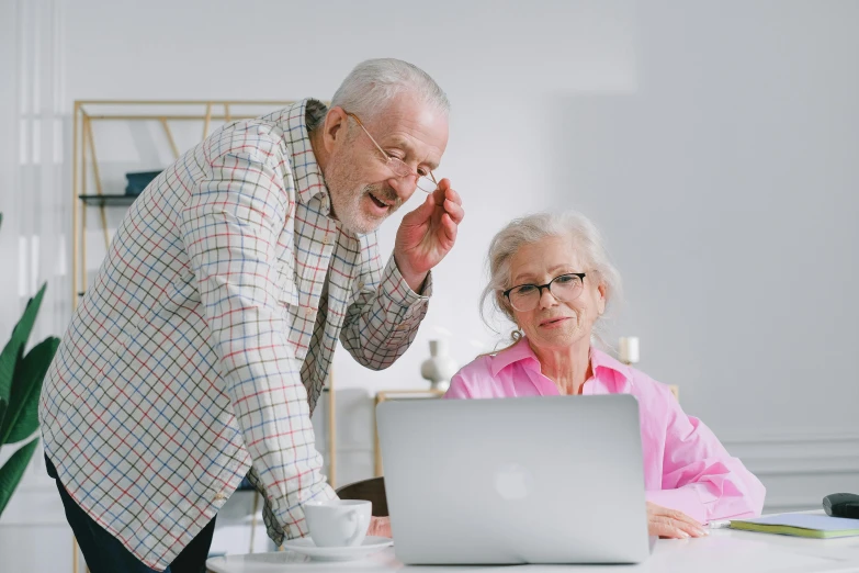 a man and woman sit at a table in front of a laptop