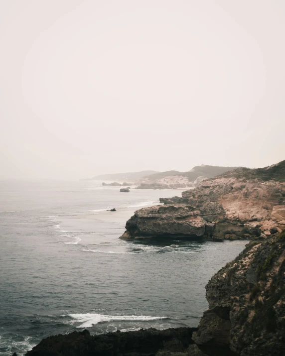 an aerial view of an ocean and rocky cliff