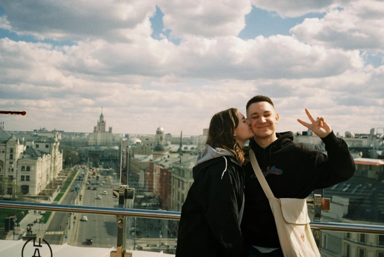 a couple of people standing on a balcony kissing