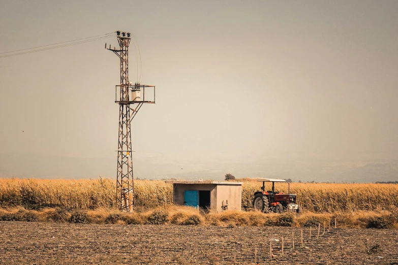 a tractor is parked next to a tower on the side of a field