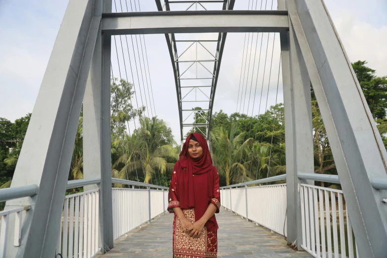 the girl is standing in the white bridge wearing a maroon scarf and a brown bag