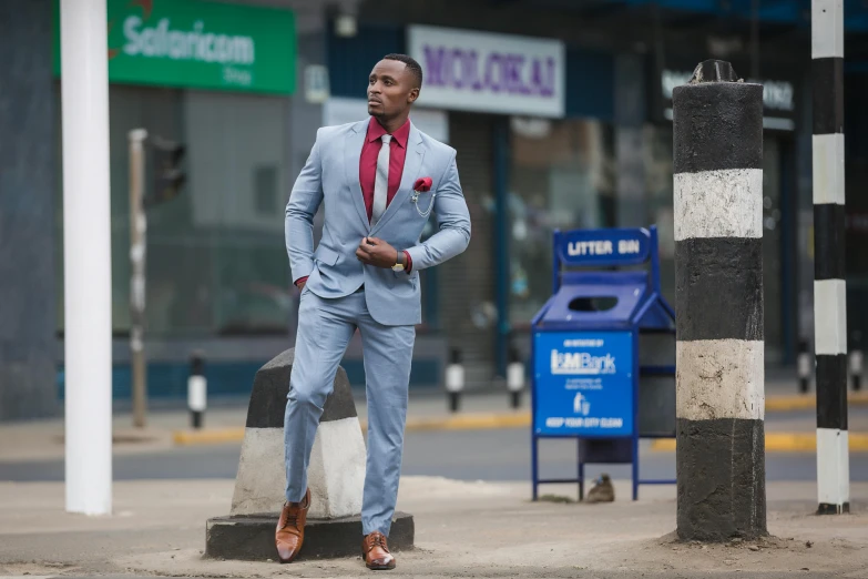 a man in a suit and tie leaning against a pillar