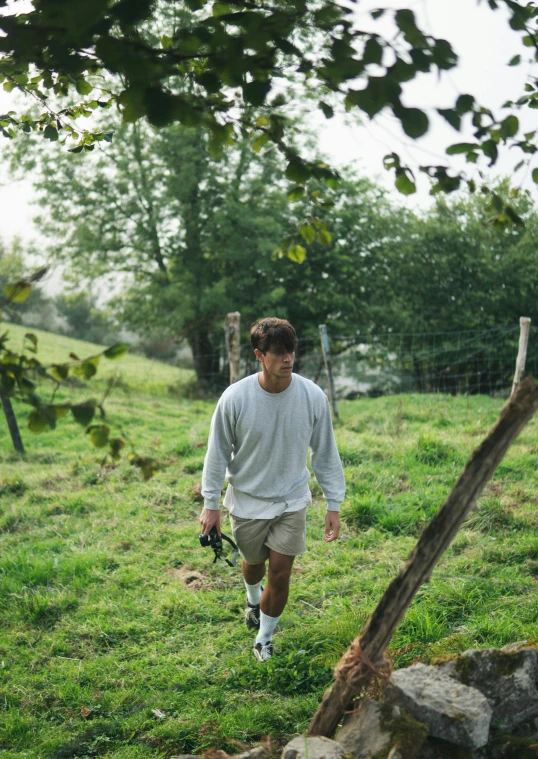 man walking in grass field holding soing in his hand