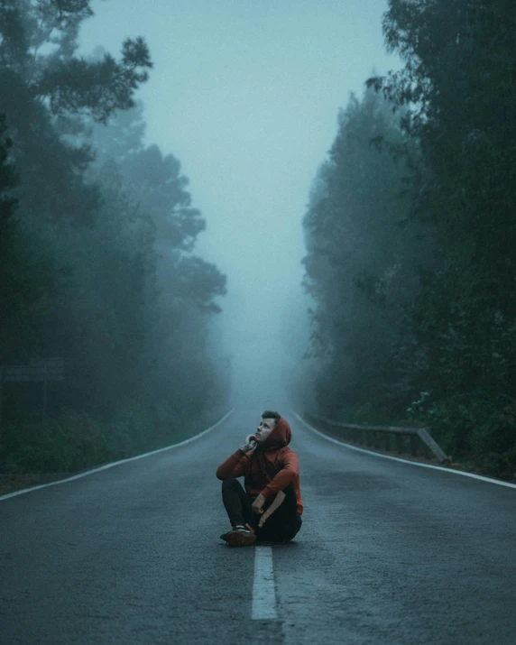 a person squatting down in the middle of a dark street