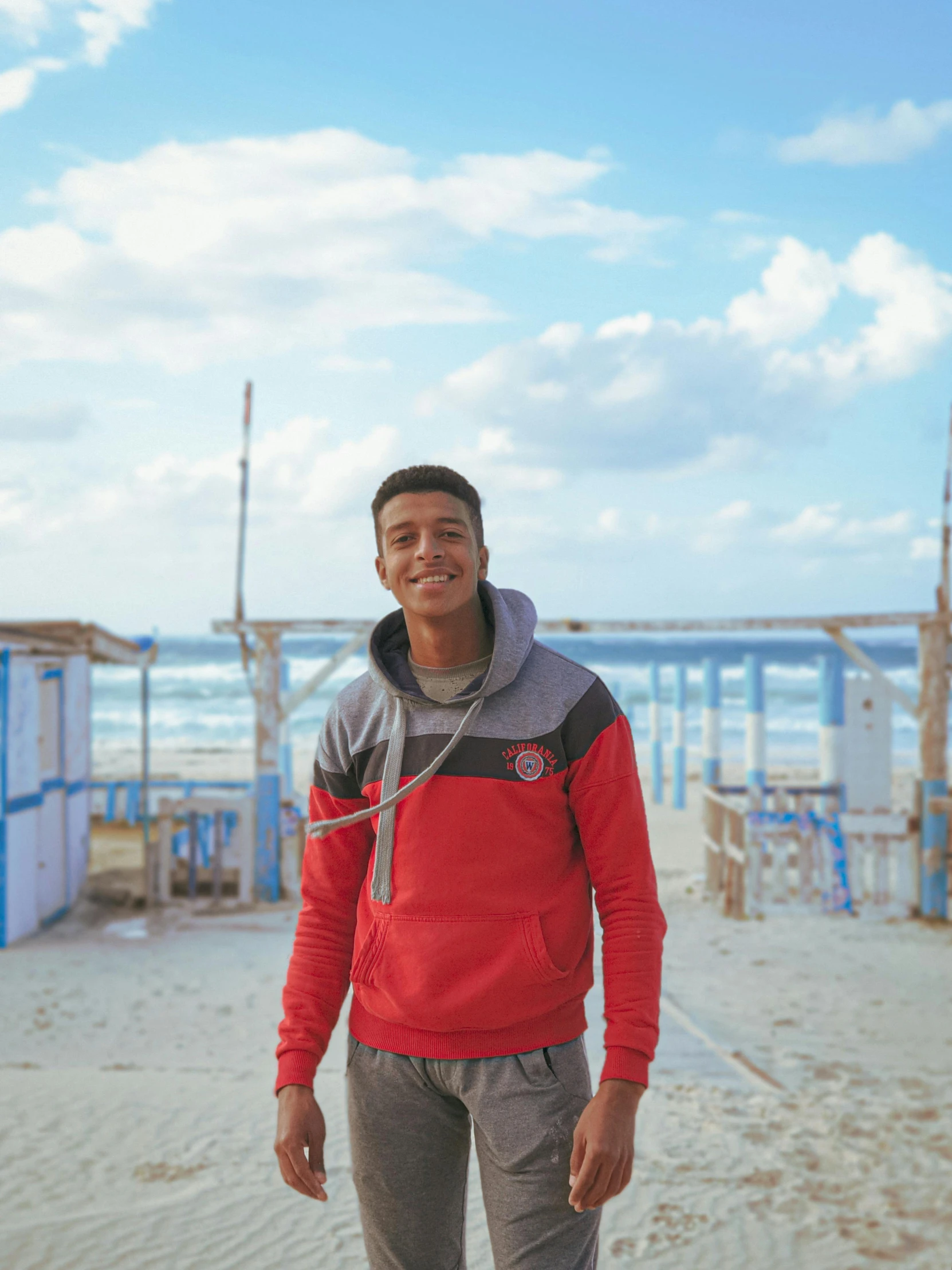 a smiling man standing in the sand on his surf board