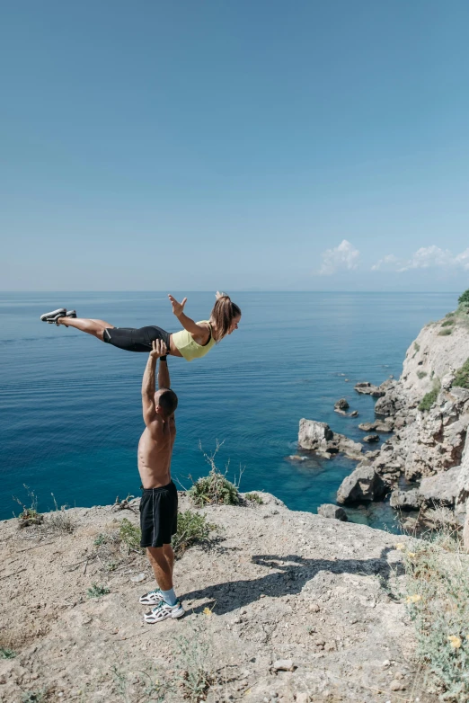 man balancing on a young child in the desert next to ocean