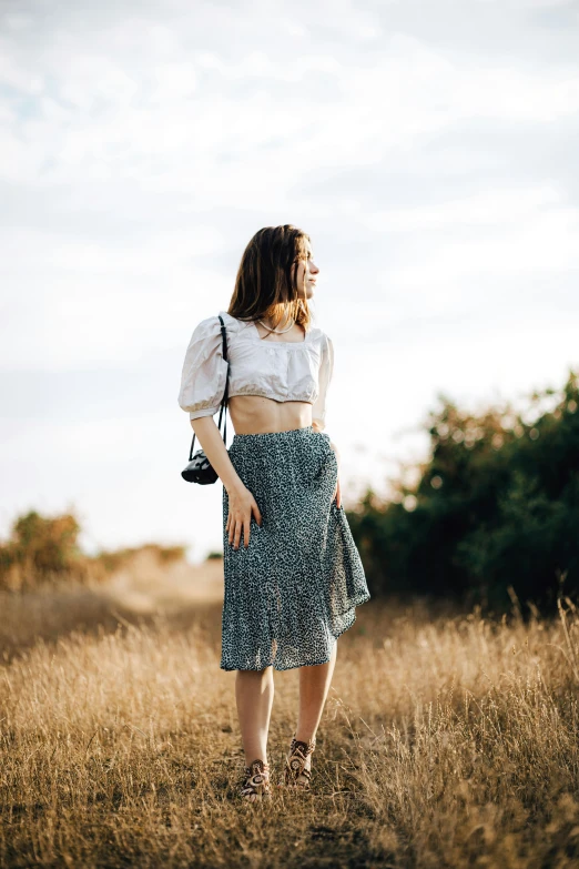 a woman wearing a top and skirt in a field